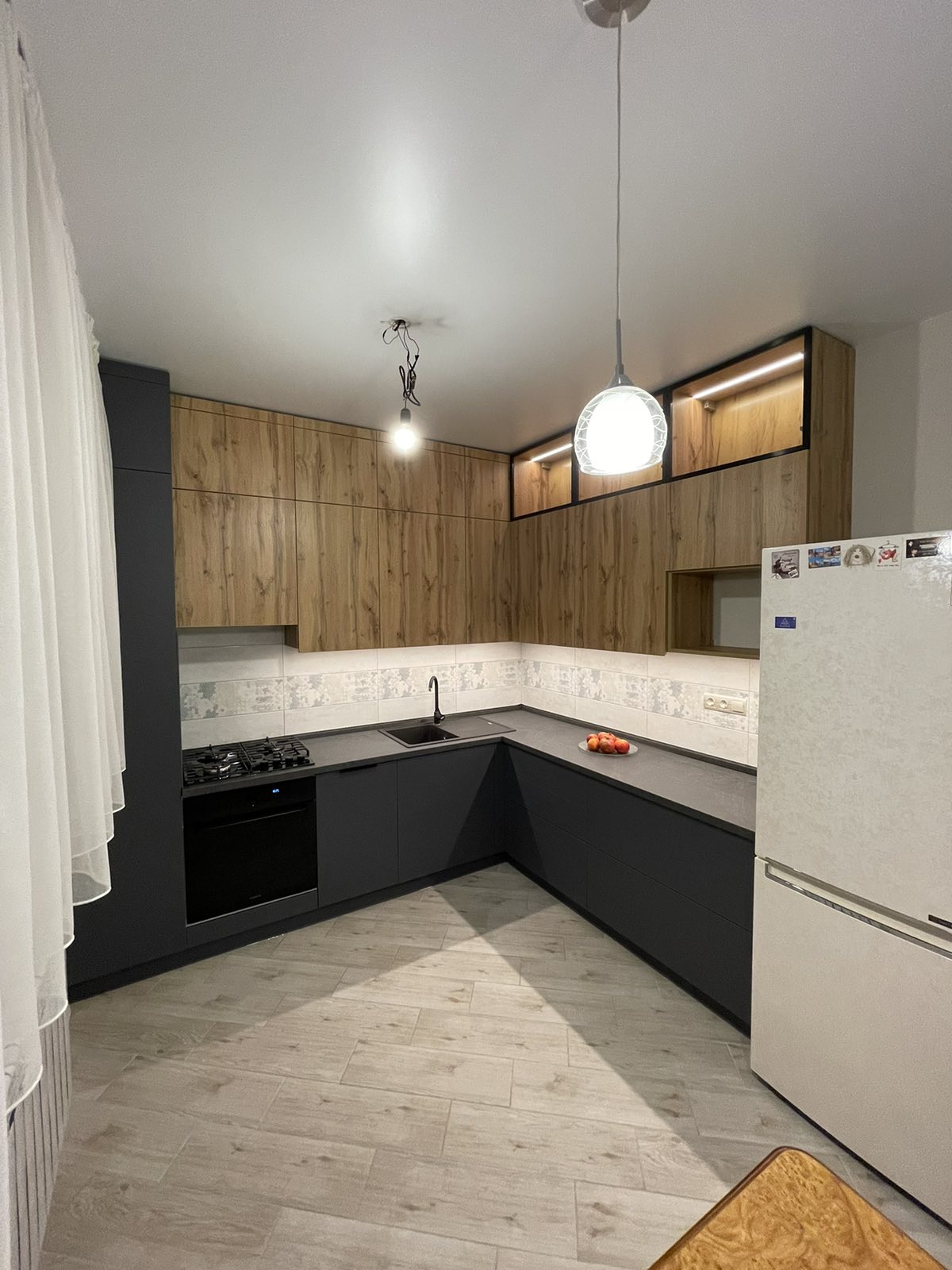 Black and white corner kitchen with timber-look overhead cabinetry