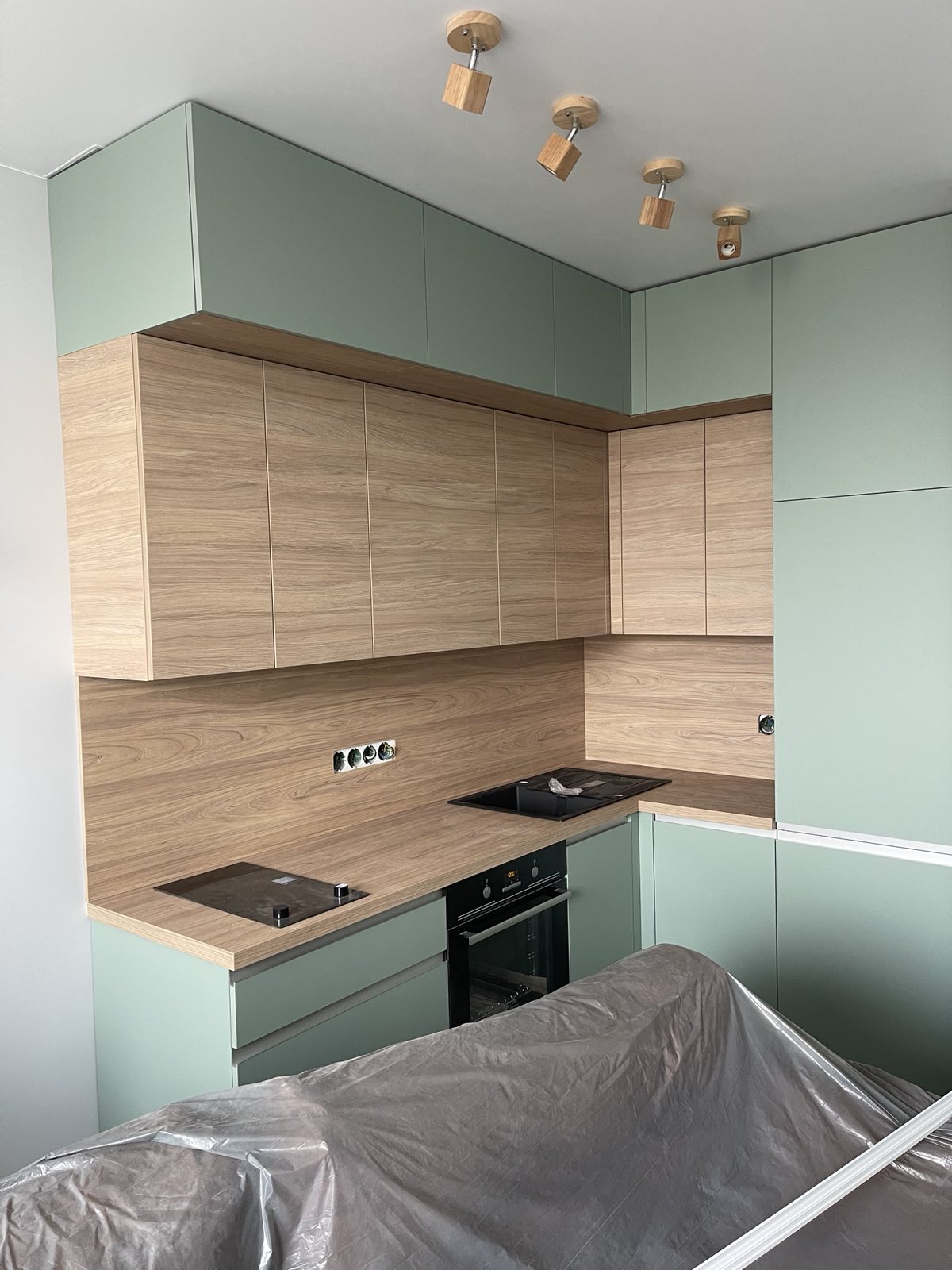 Compact sage kitchen joinery with timber-look wall panel