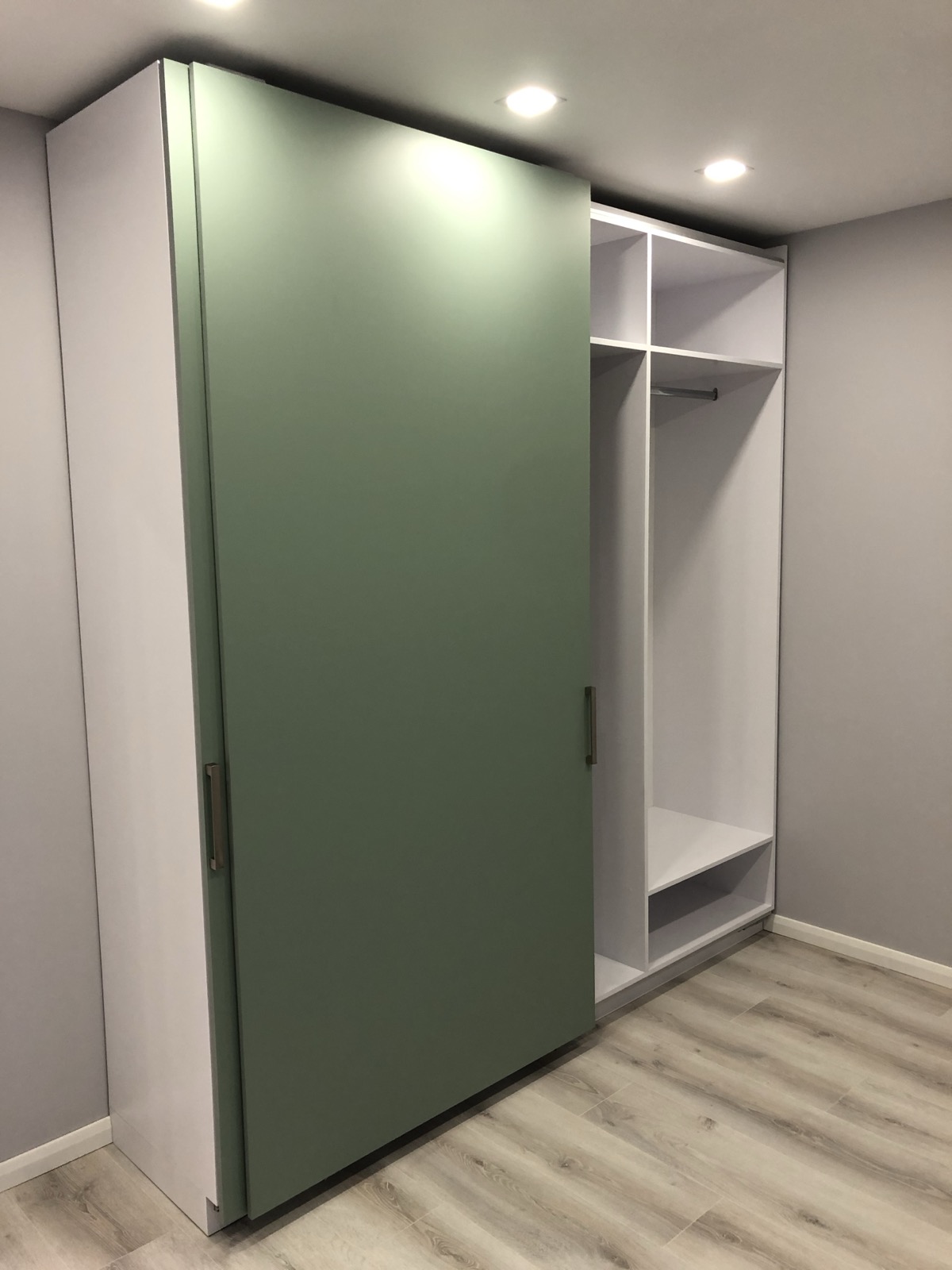 Green sliding wardrobe with open shelving and hanging storage