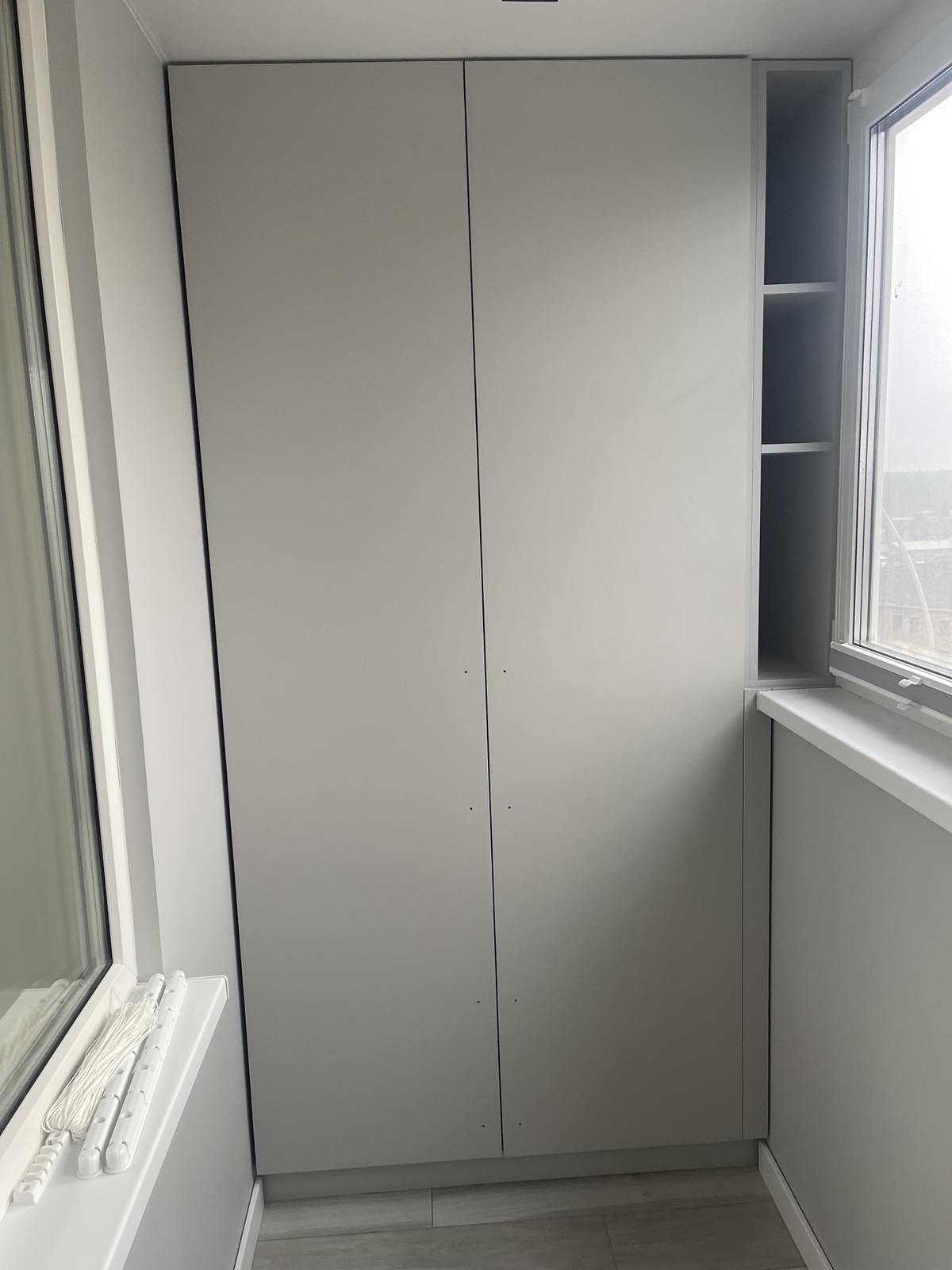 Window-side wardrobe storage with shelves and closed cabinets